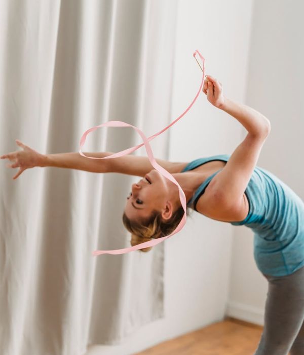 A woman in athletic wear performing rhythmic movements outdoors.